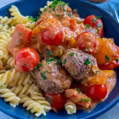 Herzhafte Hackfleisch Gerichte: saftige Hackbällchen in cremiger Tomatensoße mit Kirschtomaten und Fusilli-Nudeln, garniert mit frischer Petersilie.