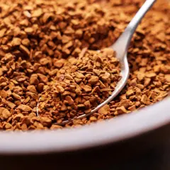 Łyżeczka pełna drobnych granulek kawy rozpuszczalnej, gotowa do zaparzenia aromatycznego espresso.