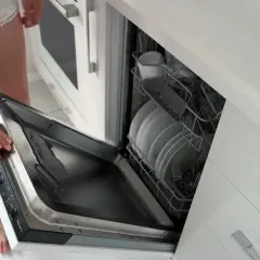 Instrukcja: jak zamontować front do zmywarki Whirlpool. Otwarta zmywarka z koszami pełnymi naczyń.
