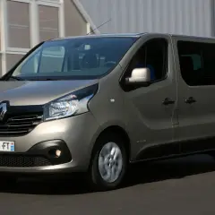 Szary Renault Trafic 3 w ruchu, z widocznym kierowcą za kierownicą.