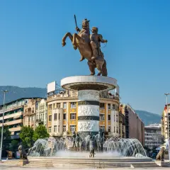 Pomnik Wojownika na koniu w centrum Skopje, stolicy Macedonii, z fontannami i budynkami w tle.