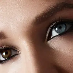 Oczy z heterochromią centralną: jedno błękitne, drugie brązowe. Rzęsy podkreślone tuszem.