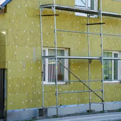 Dom w trakcie ocieplania. Widoczne wełną mineralną płyty elewacyjne, które zapobiegają powstawaniu **mostków termicznych na elewacji**.