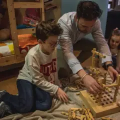 Padre e hijos construyen con bloques de madera, creando sus propios juguetes Waldorf caseros.