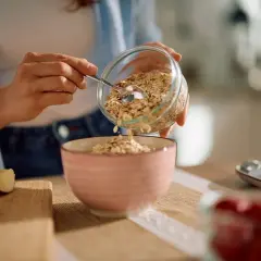 Préparation d'un petit-déjeuner sain avec des flocons d'avoine, rappelant le bon rendement avoine hectare. Des fruits frais sont à proximité.