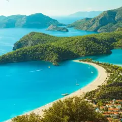 Turcja zachwyca turkusowym morzem i zielonymi wzgórzami. Widok na zatokę z plażą i łodziami.