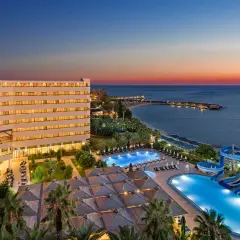 Oświetlony hotel Ozkaymak Select Resort Hotel z basenami i zjeżdżalniami wodnymi nad morzem o zachodzie słońca.