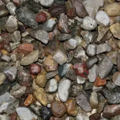 Zbliżenie na mokry żwir o różnej wielkości i kolorach, od jasnoszarego do czerwono-brązowego.