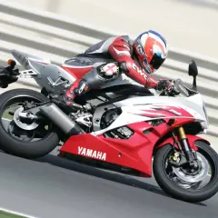 Motocyklista w czerwonym kombinezonie śmiga na torze na czerwono-białej Yamasze R6. Od ilu lat można robić prawo jazdy na motor 600? Od 20.