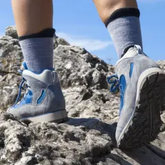 Nogi w butach trekkingowych i skarpety w góry stawiają pierwsze kroki na skalistej ścieżce.