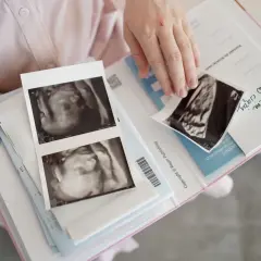 Uśmiechnięta przyszła mama przegląda zdjęcia USG. To piękny czas tycia w ciąży, jak na Mamaginekolog.