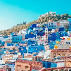 Widok na niebieskie i białe budynki miasta Chefchaouen w Maroku, na tle wzgórza.