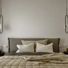 Sypialnia w stylu bauhaus z łóżkiem, poduszkami i minimalistycznymi lampami.