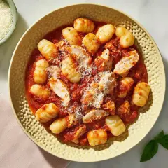 Pyszne gnocchi z kurczakiem w sosie pomidorowym, posypane parmezanem. Idealne danie na szybki obiad.