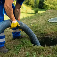 Pracownik w żółtych rękawicach obsługuje wąż do wywozu szamba. Sprawdź nasz wywóz szamba cennik i zadbaj o czystość.