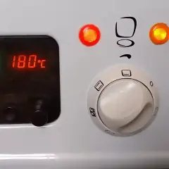 Piekarnik Mastercook: cyfrowy wyświetlacz pokazuje 180°C, a pokrętła sterują funkcjami. Czerwona lampka sygnalizuje pracę.