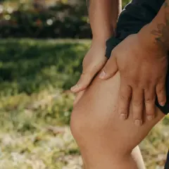 Ręce masują bolące kolano, co sugeruje rehabilitację kolana w domu.