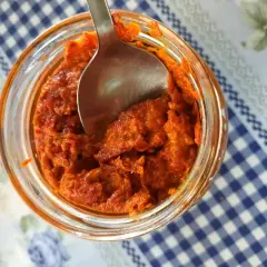 Słoik z ajwarem, pyszną pastą z papryki, gotowy do nabrania łyżką. To właśnie ajvar co to za przysmak!