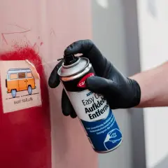 Mit einem Spray werden klebereste von kunststoffrahmen entfernt. Ein Aufkleber mit einem Camper wird gerade bearbeitet.