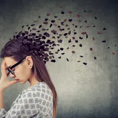Kobieta z ręką na czole, której głowa rozpada się na kawałki. Symbolizuje to trudności z koncentracją i przebodźcowaniem, często występujące jako adhd u kobiet objawy.