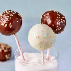 Leckere cake pops aus kuchenresten, verziert mit bunten Streuseln, stecken in einem Glas voller Zucker.