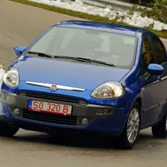 Niebieski Fiat Punto jedzie po drodze, na której widać śnieg. Z przodu widoczne są **czerwone tablice rejestracyjne** z numerem SO 320 B.