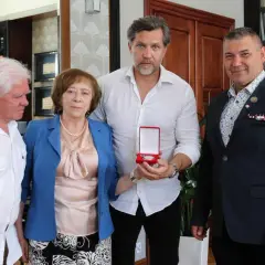 Dorota Nowakowska z mężem i dwoma mężczyznami. Jeden z nich trzyma otwarte pudełko z medalem.