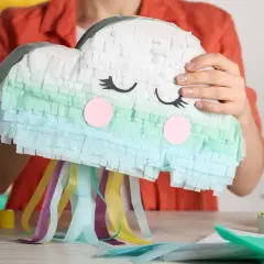 Una nuvola sorridente, una pignatta fai da te colorata con nastri svolazzanti, pronta per una festa.