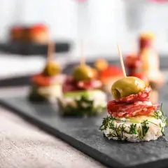 Wykwintne koreczki na imprezę: oliwka, salami i świeży koperek na chrupiącym pieczywie. Idealne na przyjęcie!