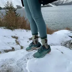 Wygodne leginsy w góry i buty do biegania na śniegu. W tle jezioro i ośnieżone szczyty.