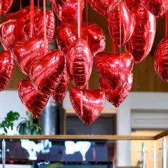 Mnóstwo błyszczących, czerwonych balonów w kształcie serc i owali, tworzących romantyczne ozdoby walentynkowe diy.