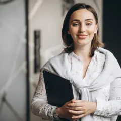 Uśmiechnięta nauczycielka z teczką, przygotowująca się do spełnienia wymagań na nauczyciela mianowanego po staremu.