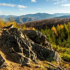 Kamienista ścieżka w Beskidach, z charakterystycznym dwernik kamień po prawej. Jesienne kolory lasu i pasmo górskie w tle.