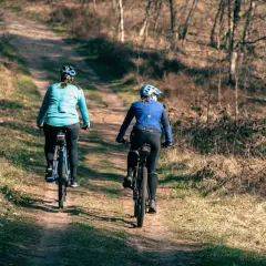 Dwie kobiety na rowerach przemierzają leśne ścieżki Roztoczańskiego Parku Narodowego.
