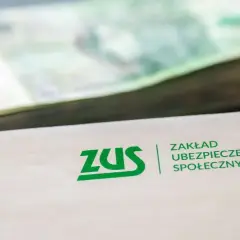 ZUS informuje, ile wynosi renta rodzinna. Stos pieniędzy i dokument z logo ZUS.