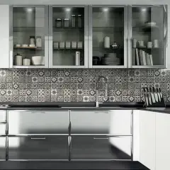 Cucina moderna con ante lucide in acciaio cromato o inox, piastrelle decorate e pensili in vetro.
