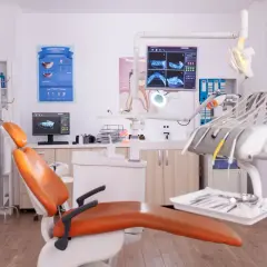 Gabinet dentystyczny gotowy na pierwsza wizyta u dentysty po latach. Pomarańczowy fotel, monitor z RTG zębów i narzędzia czekają.