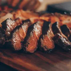 Tranches de viande juteuse sur une planche en bois. Idéal pour savoir quel vin servir avec une pierrade de viande.