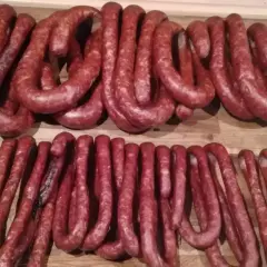 Dwie linie wędzonych kiełbasek, ułożonych w kształt podkowy. Zastanawiam się, ile pieprzu do kiełbasy dodano, by uzyskać ten smak.