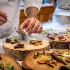 Szef kuchni serwuje danie z grzybami i mgłą, tworząc magiczną atmosferę w jednej z nietypowych restauracji w Warszawie.