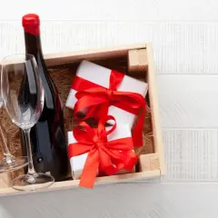 Cadeau gourmand : une bouteille de vin rouge, deux verres et des présents emballés, prêts à être dégustés dans un domaine de Bourgogne.