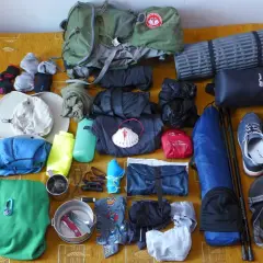 Przygotowania do camino de santiago: plecak, buty, śpiwór, karimata, ubrania, czapka, kijki i muszla pielgrzyma.
