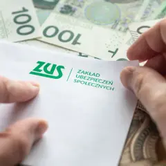 Dłonie trzymają dokument ZUS na tle banknotów 100 zł. Może to być związane z jednorazową wypłatą z subkonta ZUS.