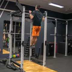 Mężczyzna wykonuje podciąganie na drążku w siłowni. To element skutecznego powerlifting plan treningowy.