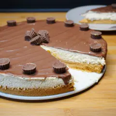 Reese's Torte mit Schokoladenglasur und Erdnussbutter-Cups. Ein Stück ist bereits angeschnitten.