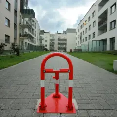 Czerwony słupek blokujący na ścieżce między nowoczesnymi budynkami mieszkalnymi.