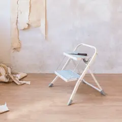 Tapete entfernen ist zeitaufwendig. Ein kleiner Tritt, Werkzeug und Tapetenreste liegen auf dem Holzboden.