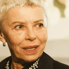 Kobieta z krótkimi siwymi włosami, w czarnej bluzce z perełkami, opowiada o tym, jak zostać aktorką.