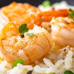 Delicioso arroz con gambas y verduras, adornado con hierbas frescas y granos de pimienta.