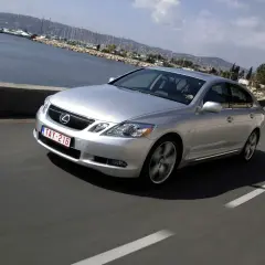 Srebrny Lexus GS300 MK3 pędzi wzdłuż malowniczego wybrzeża z widokiem na zatokę pełną jachtów.